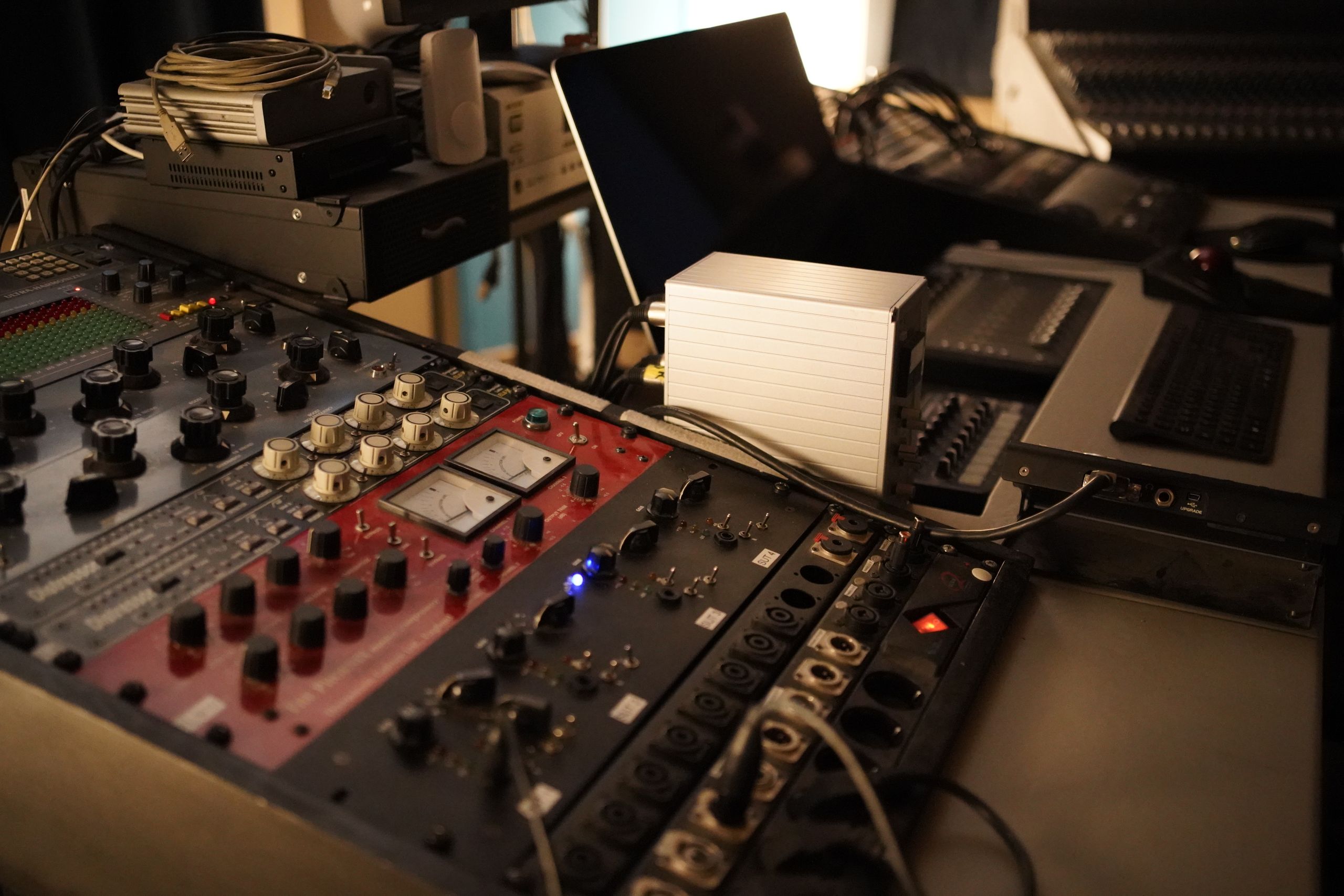 Close-up view of an audio mixing console with various controls in a professional recording studio.